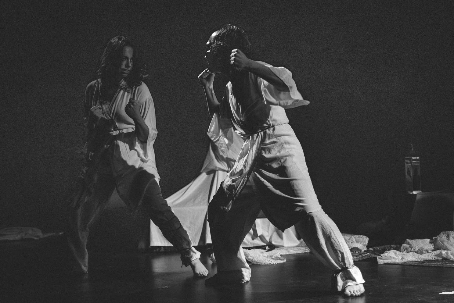 Two masked performers mid-movement, in black and white